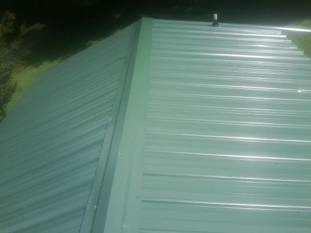 New green metal panels meeting at the ridge of a roof — Flat Roof Repair work by our crew in Crystal River