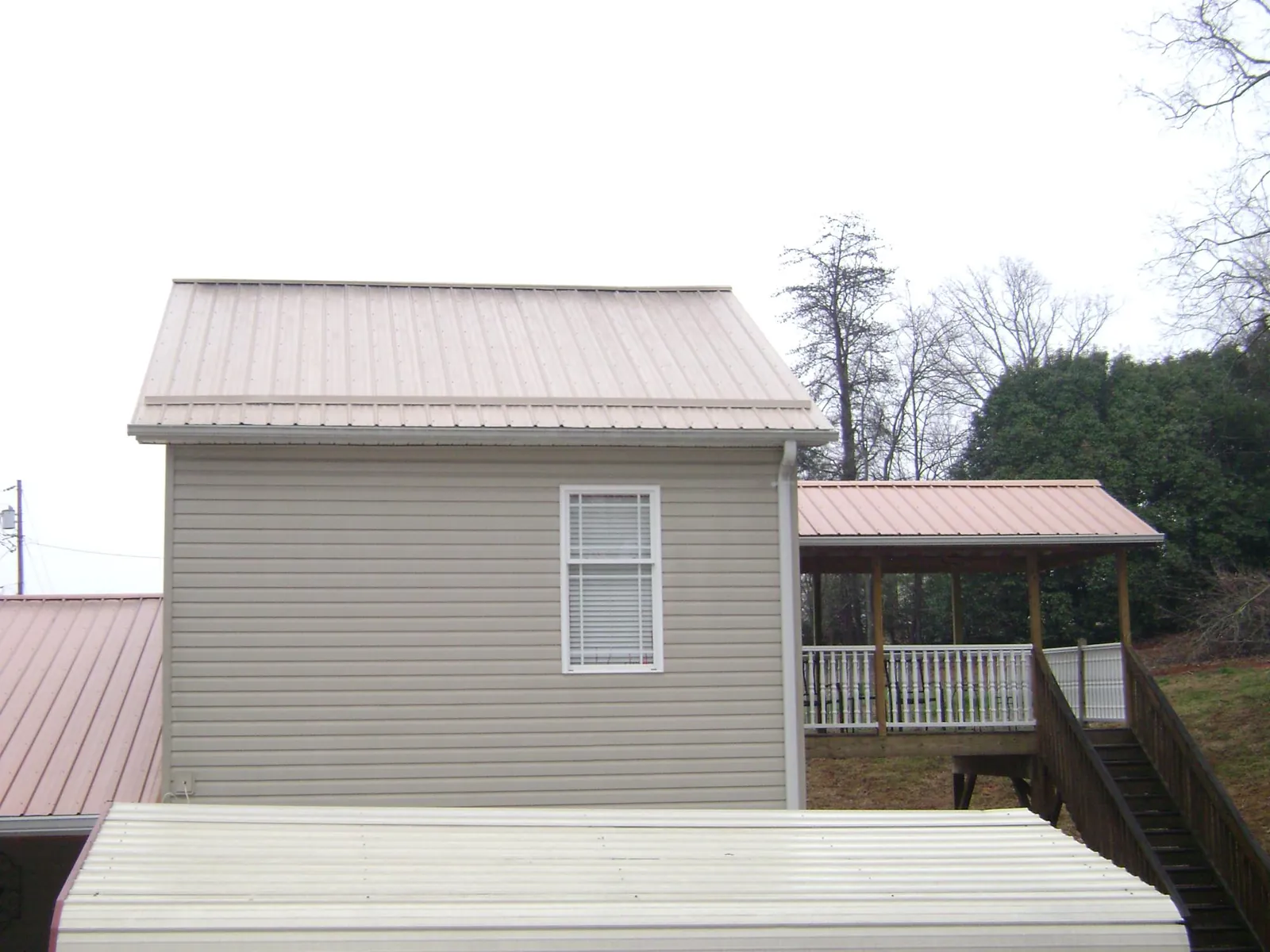 Tan metal roofs on a two story addition and attached porch, from a Roof Replacement job in Crystal River